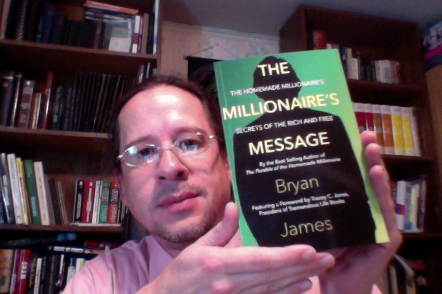 Publisher Tony Michalski poses with Bryan James's new book "The Millionaire's Message: The Homemade Millionaire's Secrets of the Rich and Free."